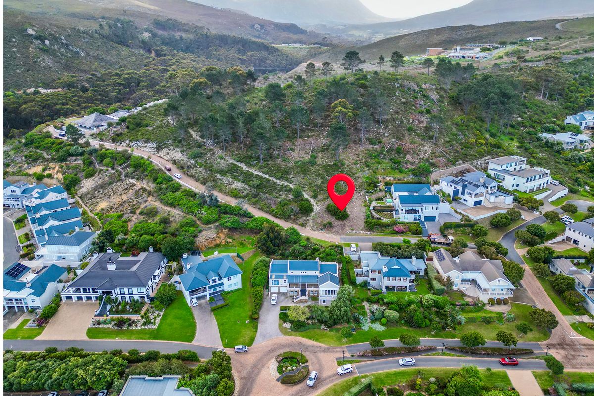 An aerial view of a vacant residential plot situated within an established estate, featuring scenic mountain views and surrounding residential development.