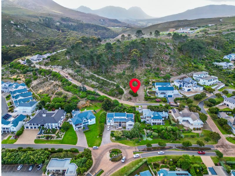 An aerial view of a vacant residential plot situated within an established estate, featuring scenic mountain views and surrounding residential development.