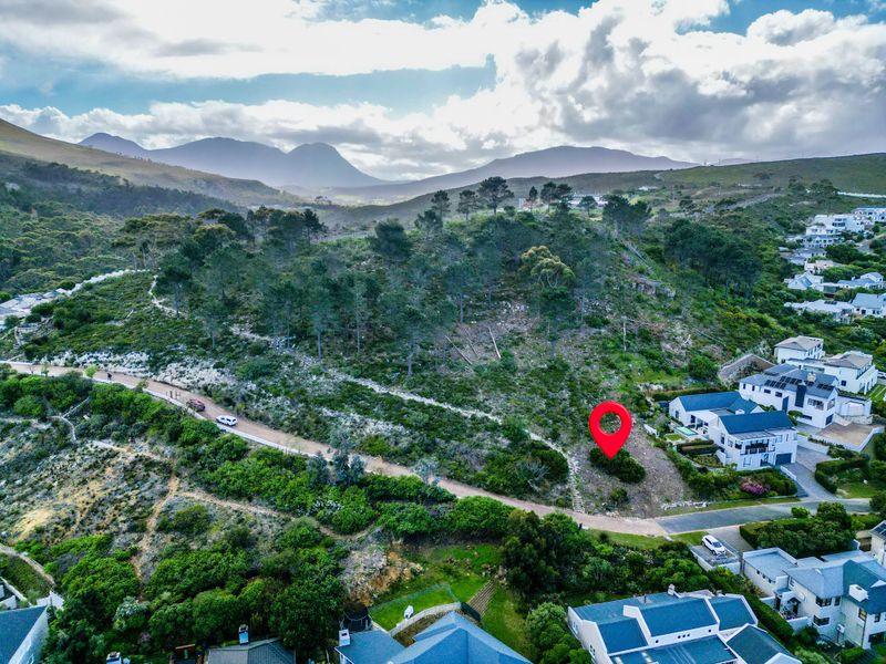 Aerial view of a vacant residential plot featuring sloped terrain and native vegetation, situated in a scenic hillside neighborhood.