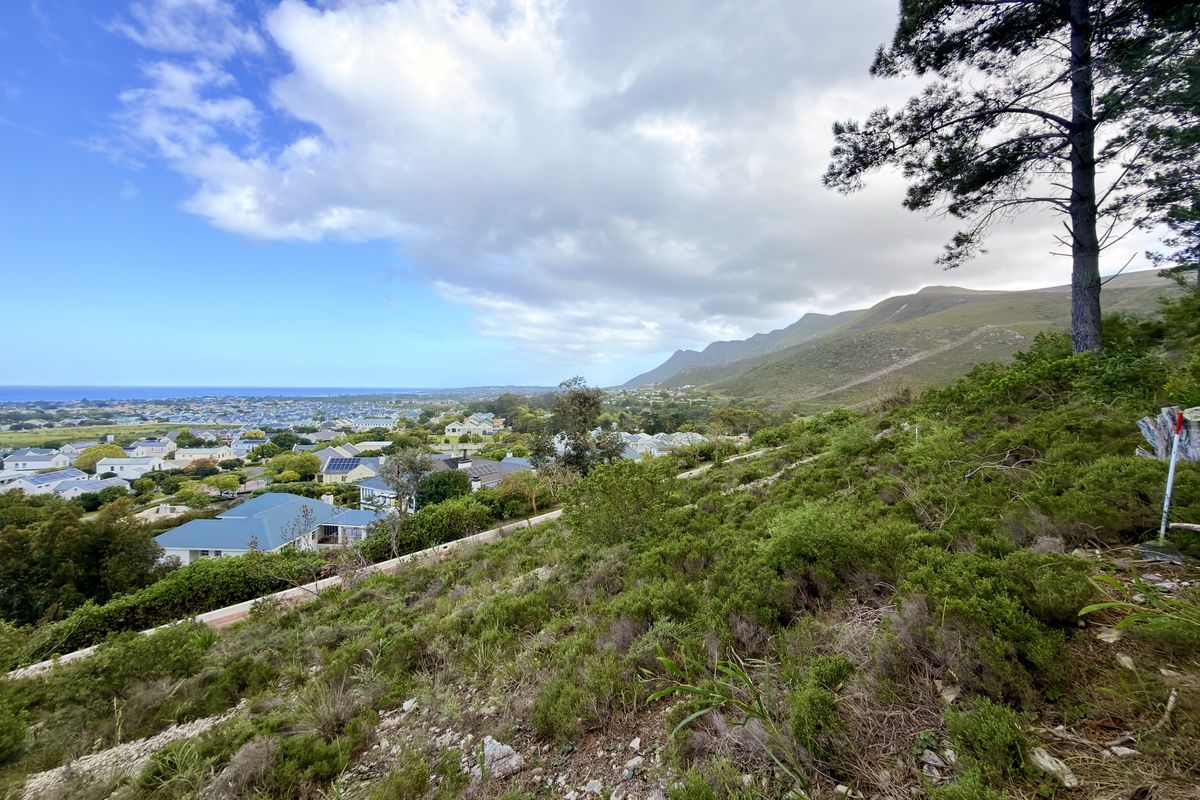 Elevated view overlooking the residential estate, surrounding landscape, and distant coastline from the sloped vacant land.