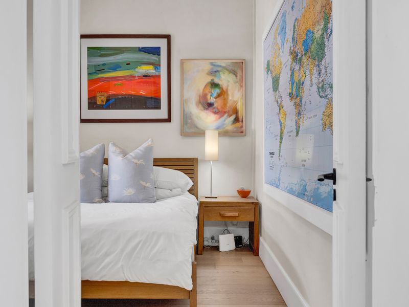 A cozy bedroom featuring hardwood flooring and classic double door entry, presented in a clean and well-maintained condition.