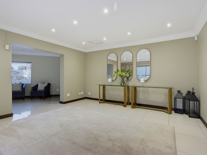 A spacious, well-maintained living area featuring neutral tiled flooring, recessed downlighting, and elegant coved cornicing, creating a bright and inviting atmosphere.