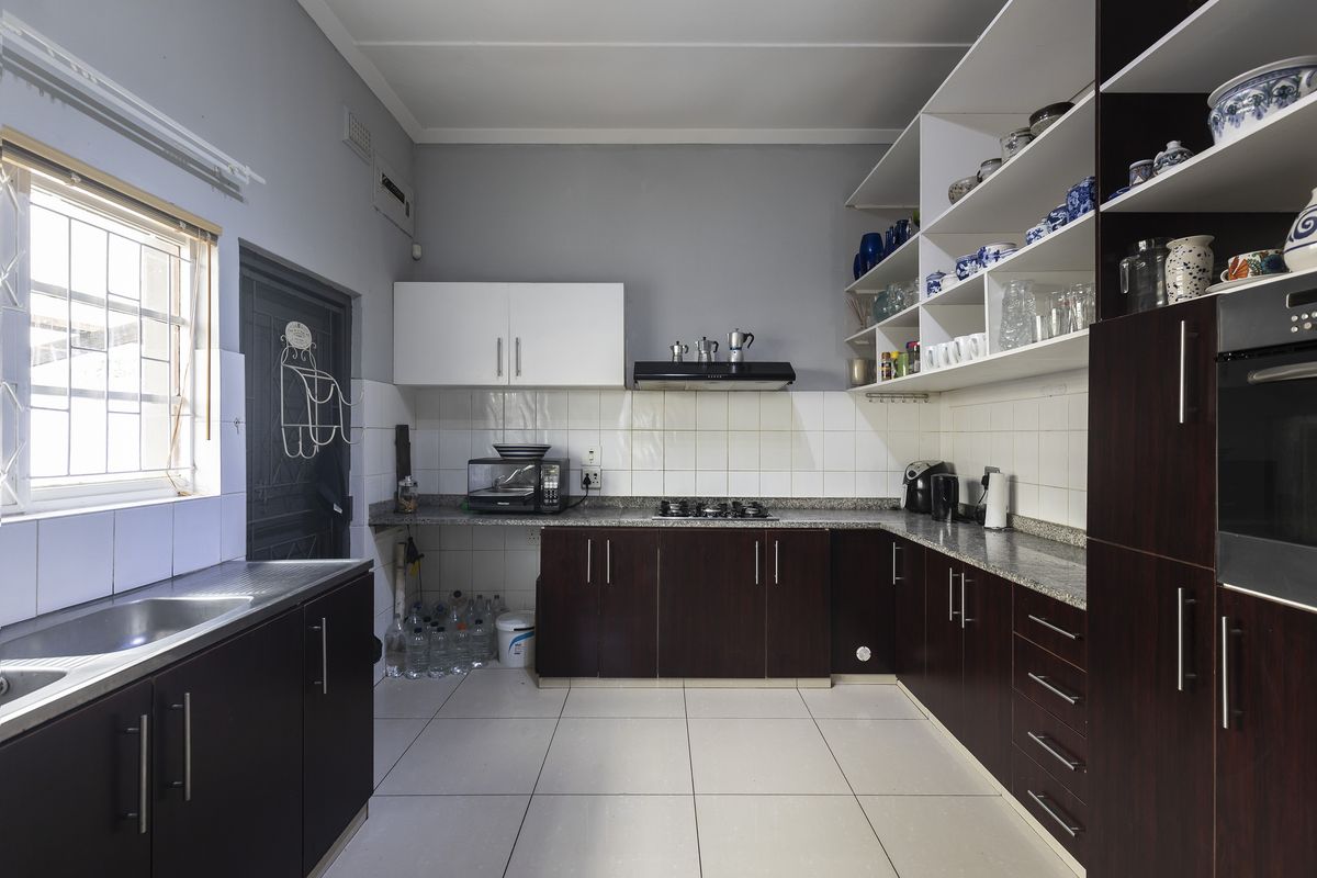 Functional kitchen featuring dark wood cabinetry, granite countertops, gas hob, built-in oven, and ample open shelving for storage.
