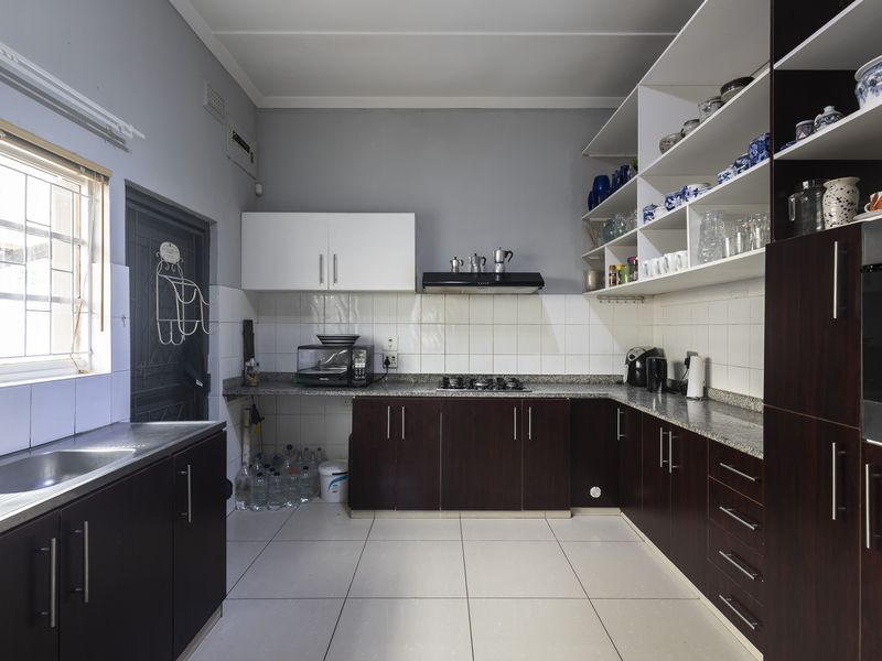 Functional kitchen featuring dark wood cabinetry, granite countertops, gas hob, built-in oven, and ample open shelving for storage.