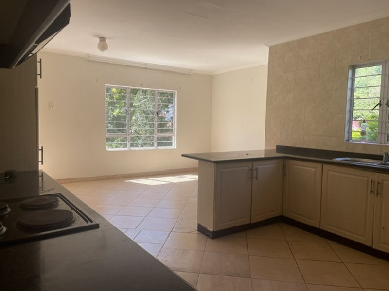 Spacious open-plan kitchen and living area featuring tiled flooring, built-in cabinetry with granite countertops, and an integrated electric hob.