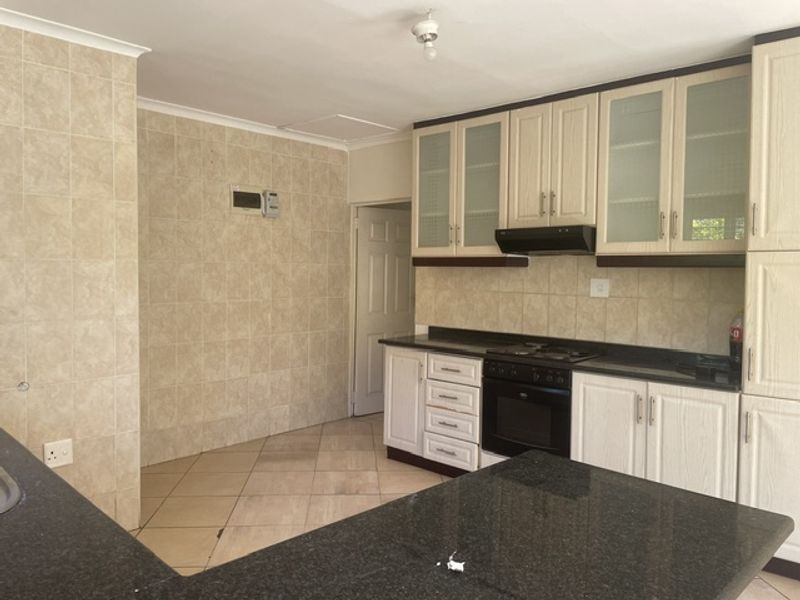 A functional kitchen featuring built-in cabinetry, granite countertops, an integrated oven and hob, and tiled splashbacks throughout.