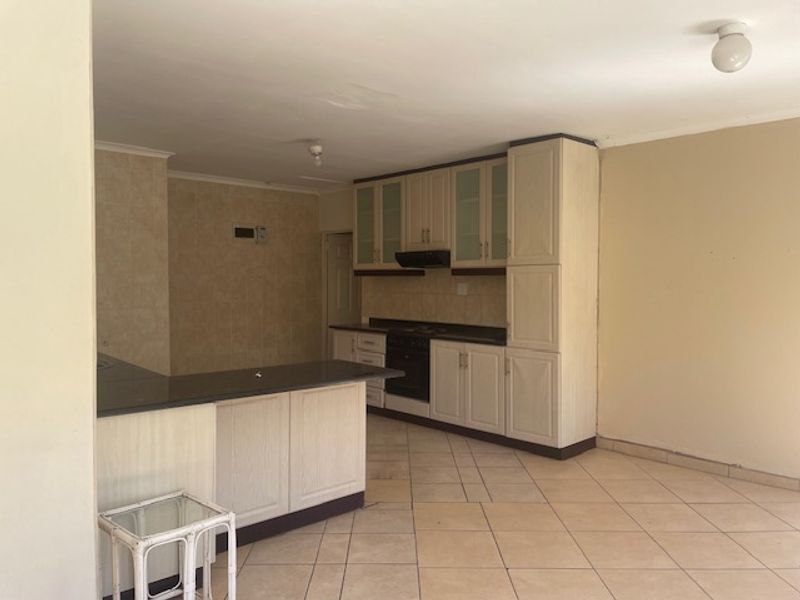 An empty kitchen featuring built-in cabinetry, granite countertops, a built-in oven with extractor fan, and tiled flooring with an integrated breakfast nook.