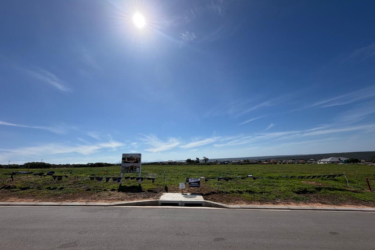 A vacant residential plot of land featuring a clear street frontage, concrete curb, and stormwater drainage infrastructure, ready for development.