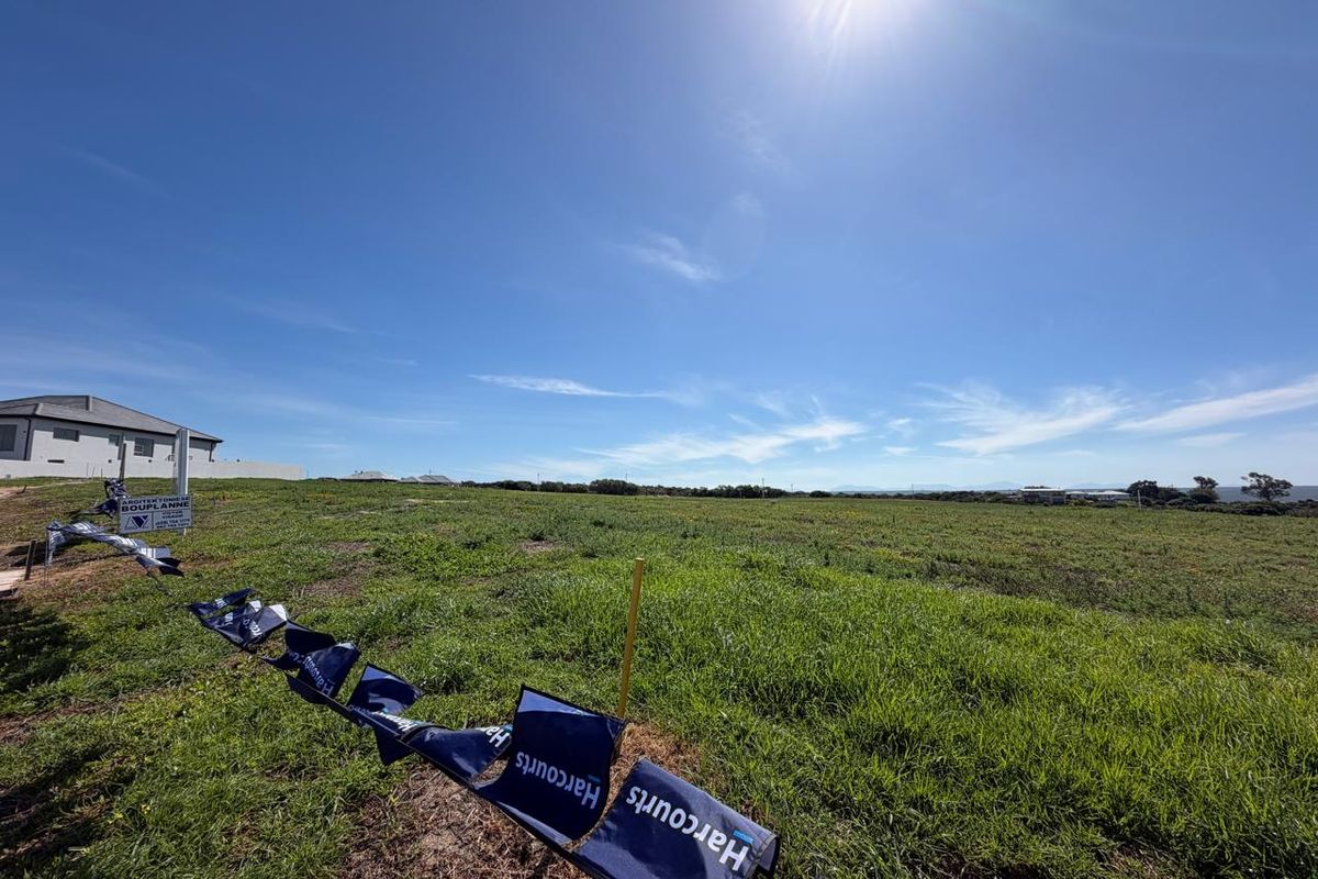 A wide-angle view of a vacant residential plot of land featuring natural grass coverage and clear boundary markers.