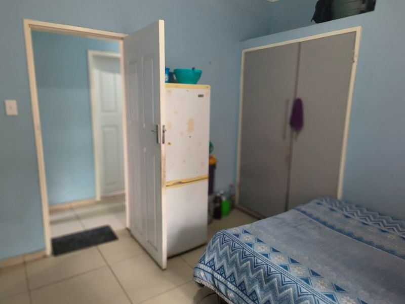 A bedroom featuring tiled flooring and a built-in wardrobe, currently showing signs of wear and requiring cosmetic updates.