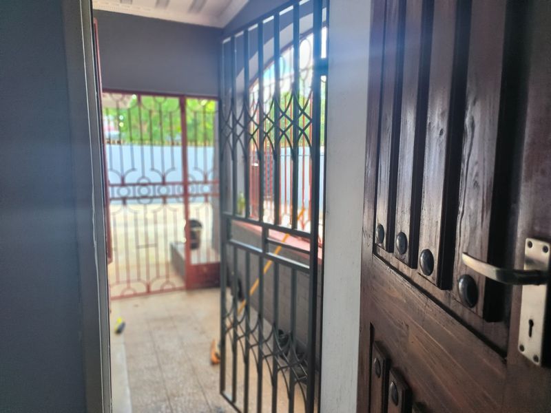 An entryway featuring a solid timber door and a metal security gate leading to an outdoor area.
