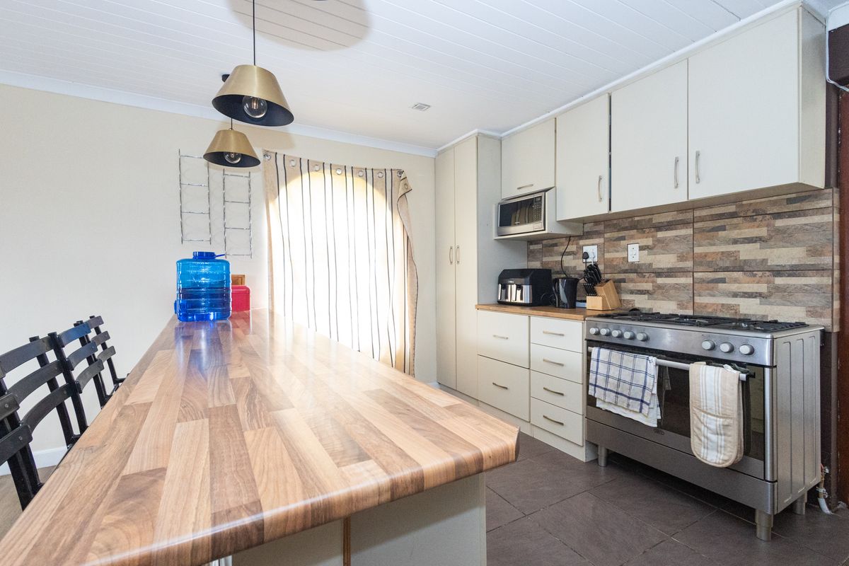 A functional kitchen featuring built-in cabinetry, a gas stove with oven, a built-in microwave, and a spacious timber-look breakfast bar.