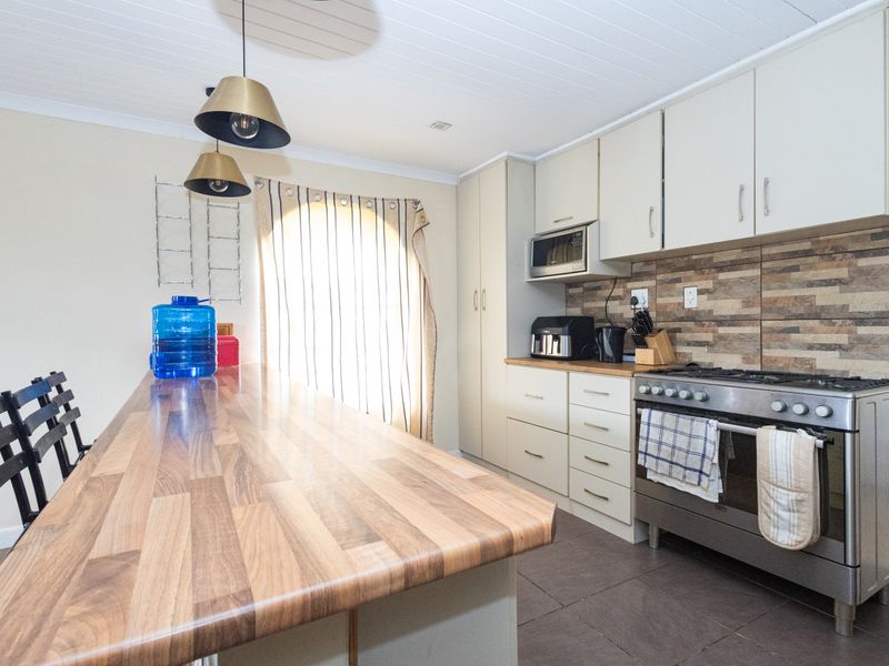 A functional kitchen featuring built-in cabinetry, a gas stove with oven, a built-in microwave, and a spacious timber-look breakfast bar.