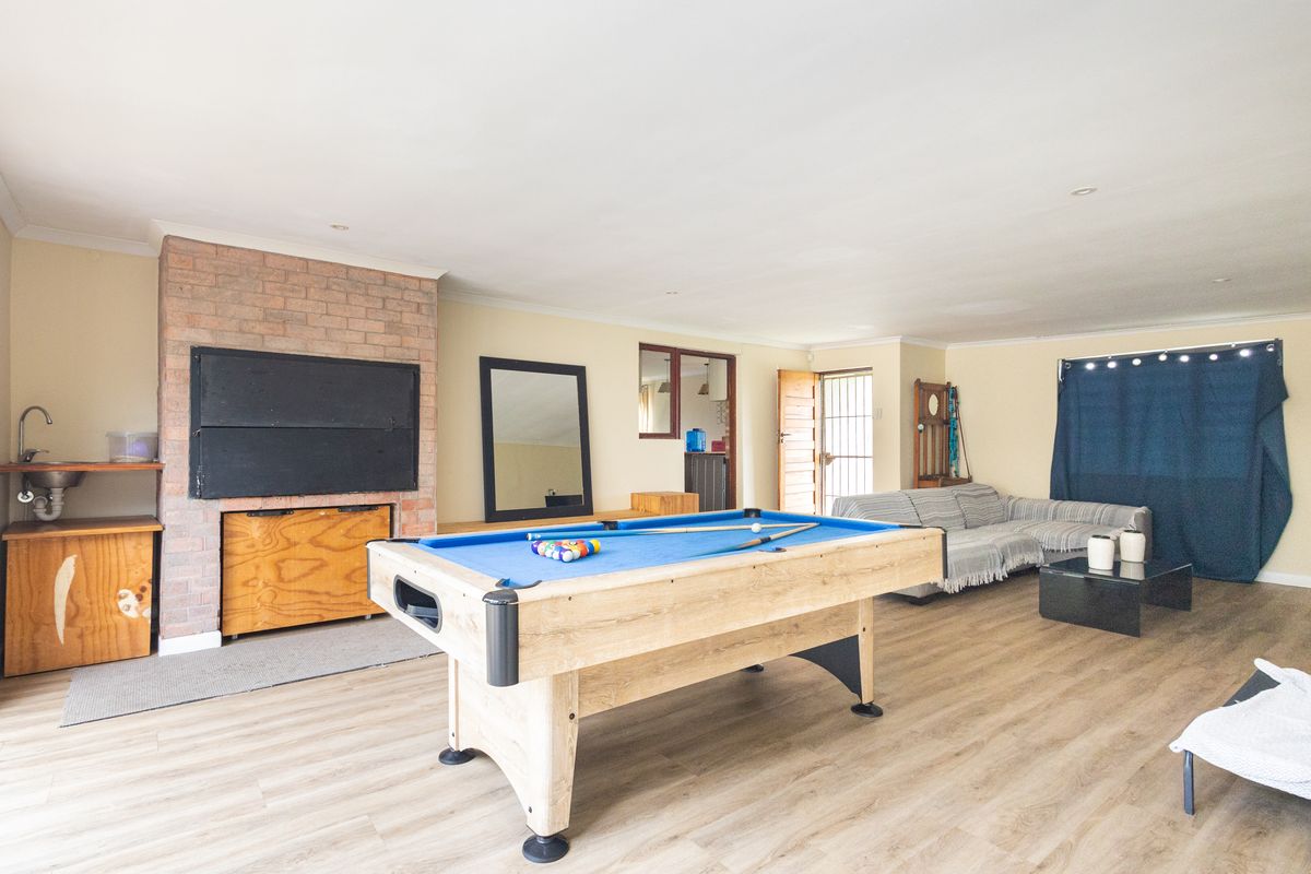 Spacious living area featuring a brick fireplace, built-in sink, and durable laminate flooring, offering a versatile space for relaxation and entertainment.