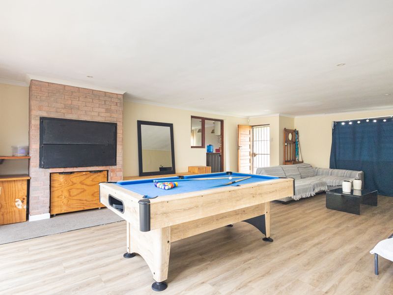 Spacious living area featuring a brick fireplace, built-in sink, and durable laminate flooring, offering a versatile space for relaxation and entertainment.