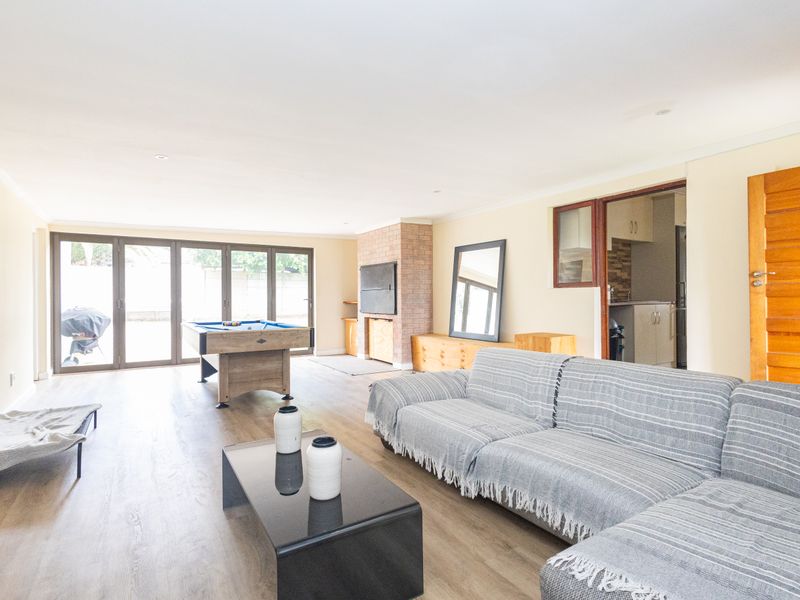 Spacious open-plan living area featuring laminate flooring, a brick fireplace, and large stacking glass doors providing seamless access to the outdoor space.