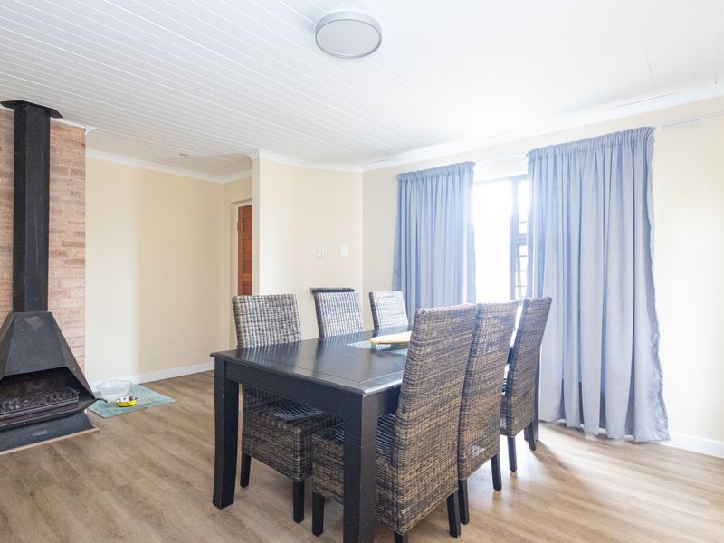 Dining room featuring a brick fireplace, laminate flooring, and a tongue and groove ceiling, offering a cozy and functional space.