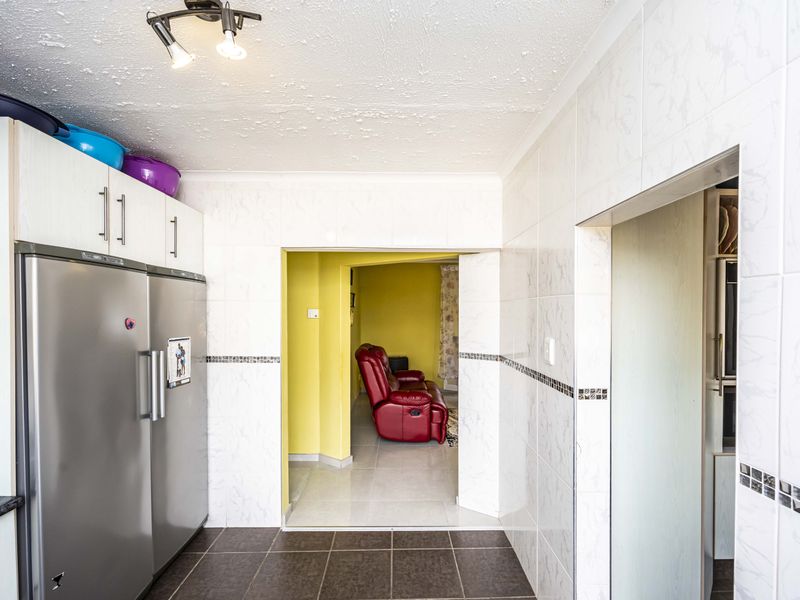 A functional kitchen area featuring tiled walls, tiled flooring, and built-in cabinetry, providing a clean and practical workspace.