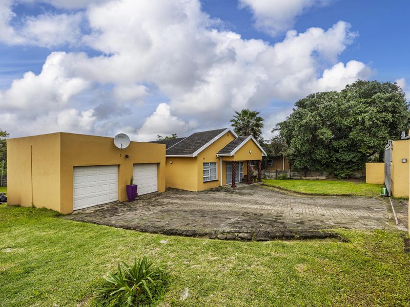 Front view of a single-story house featuring a double garage, paved driveway, and established garden area.