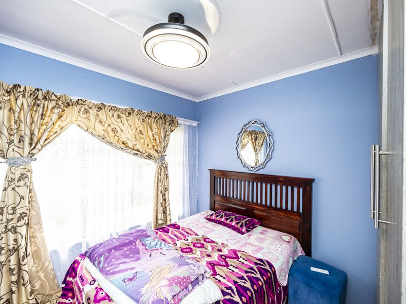 A bedroom featuring blue walls, a ceiling fan, and a built-in wardrobe, with some visible wear on the ceiling finishes.