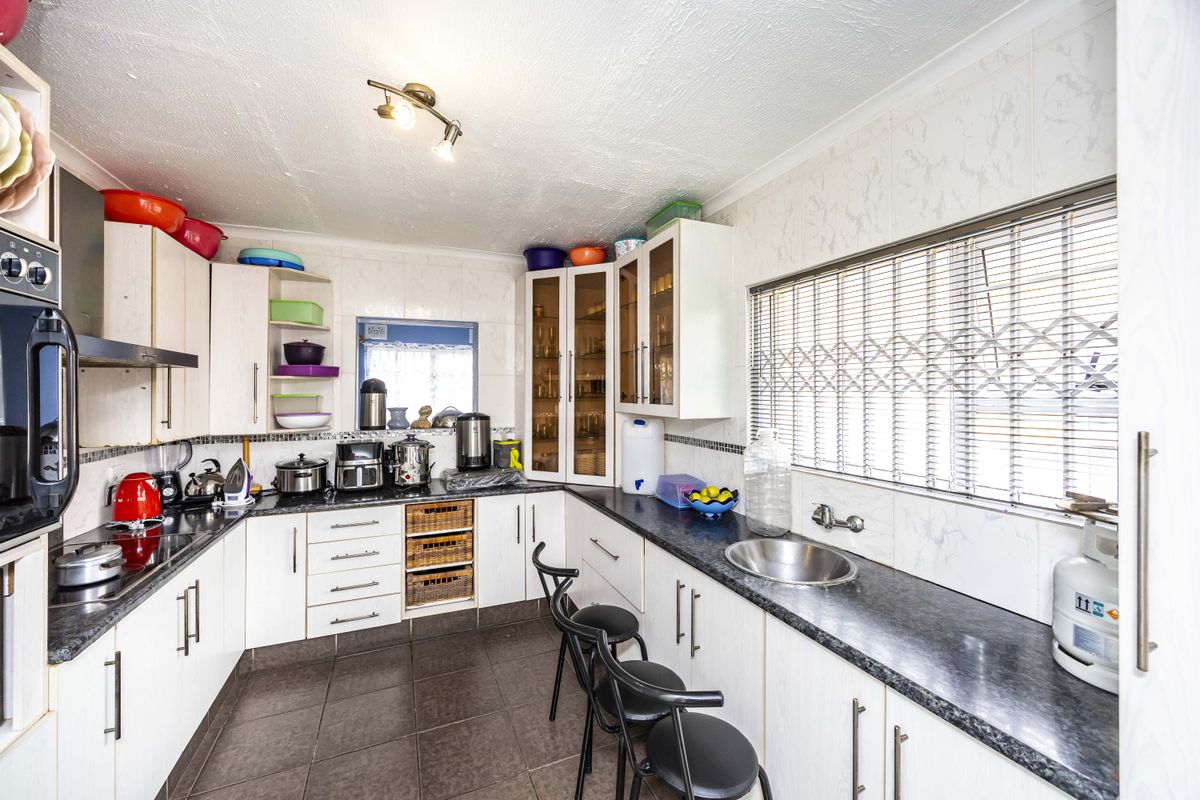 Functional kitchen featuring ample built-in cabinetry, laminate countertops, a stainless steel sink, and a built-in oven with an extractor fan.