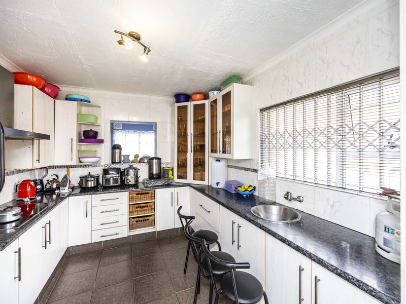 Functional kitchen featuring ample built-in cabinetry, laminate countertops, a stainless steel sink, and a built-in oven with an extractor fan.