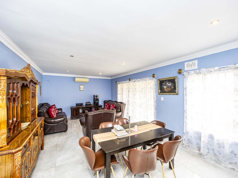Spacious open-plan living and dining area featuring tiled flooring, crown molding, recessed lighting, and a wall-mounted air conditioning unit.