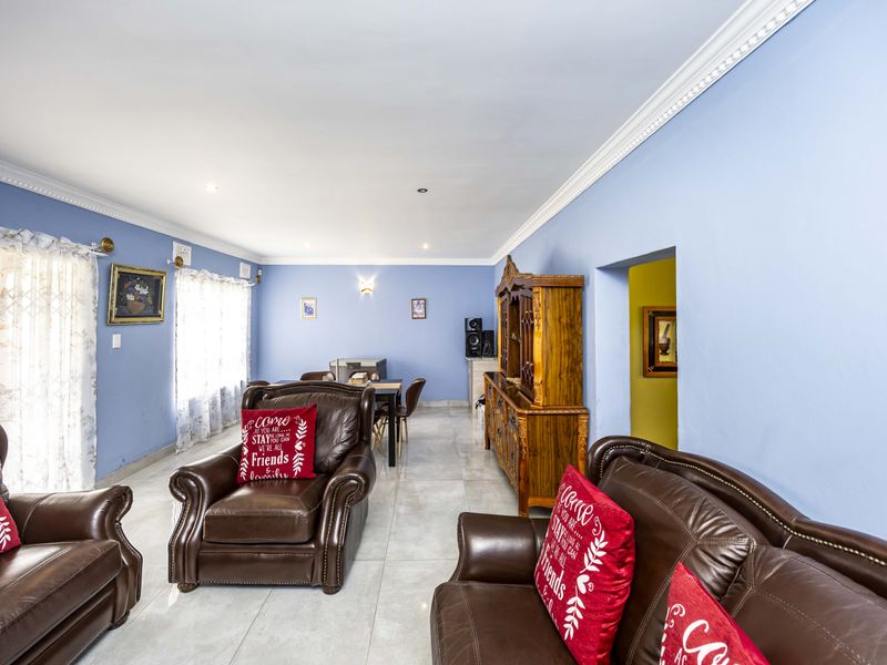 Spacious open-plan living and dining area featuring tiled flooring, crown molding, and neutral blue walls, offering a versatile layout for family living.