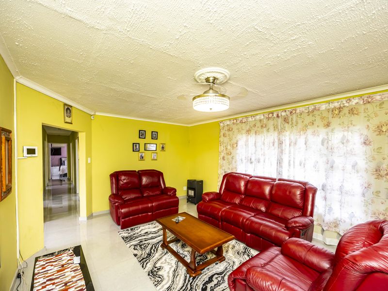 A living room featuring tiled flooring, a ceiling fan with a decorative rose, and coving, providing a functional space for relaxation.