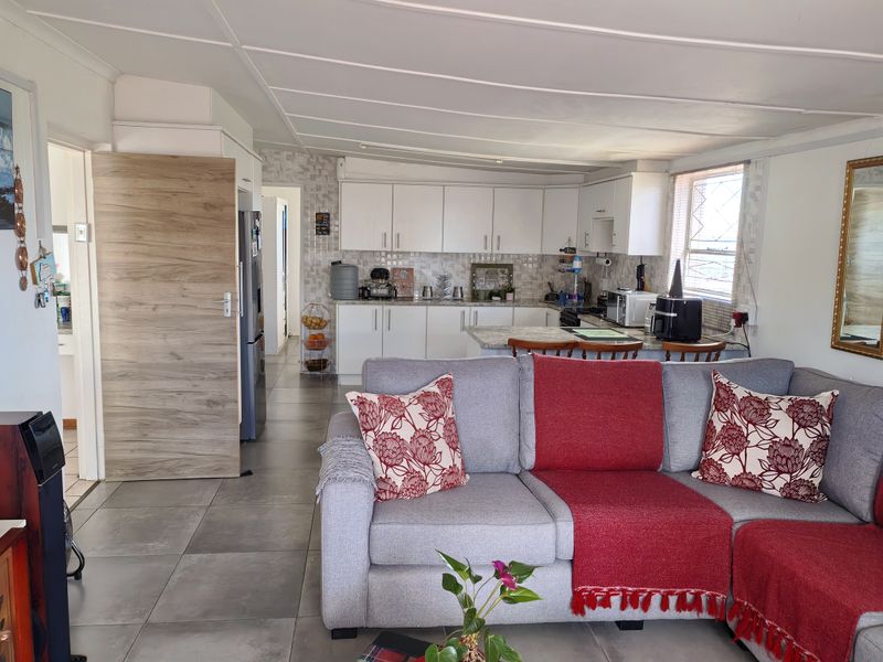 Open-plan living area featuring a functional kitchen with built-in cabinetry, stone countertops, and a breakfast bar, seamlessly connected to the lounge space.