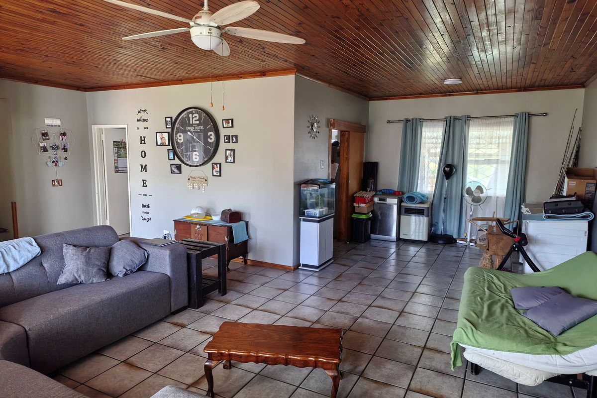 Spacious living area featuring a timber tongue and groove ceiling, ceiling fan, and ceramic tiled flooring throughout.