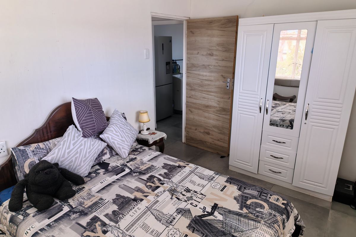A functional bedroom featuring tiled flooring and a built-in wardrobe, with direct access to an adjacent utility area.