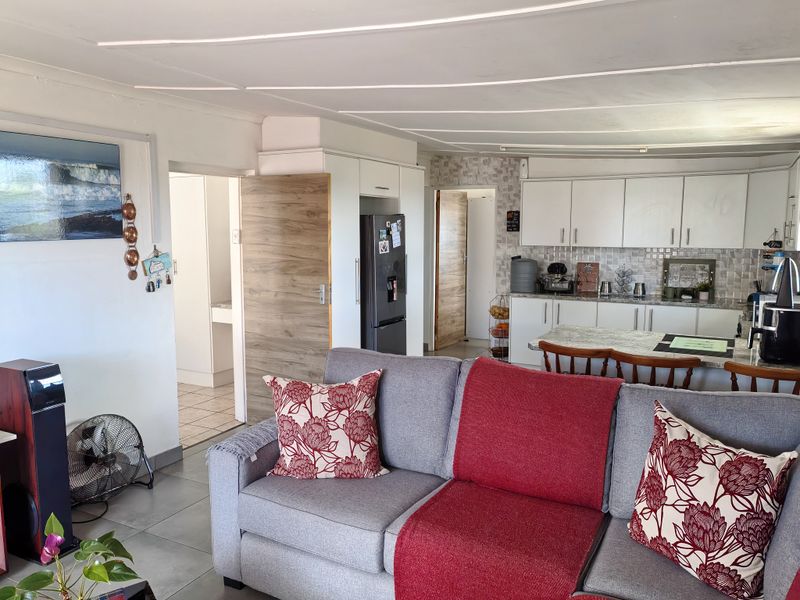 Open-plan living area featuring a functional kitchen with white cabinetry, a central island, and tiled flooring throughout the connected space.