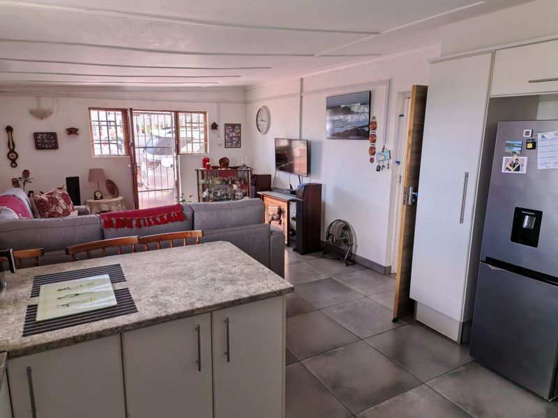 Open-plan living area featuring a kitchen island with laminate countertop, tiled flooring, and direct access to the exterior via a security gate.