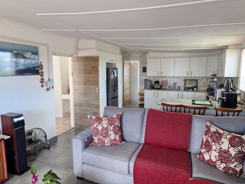 Open plan living area featuring a functional kitchen with white cabinetry, stone countertops, and tiled flooring, seamlessly connected to the lounge space.