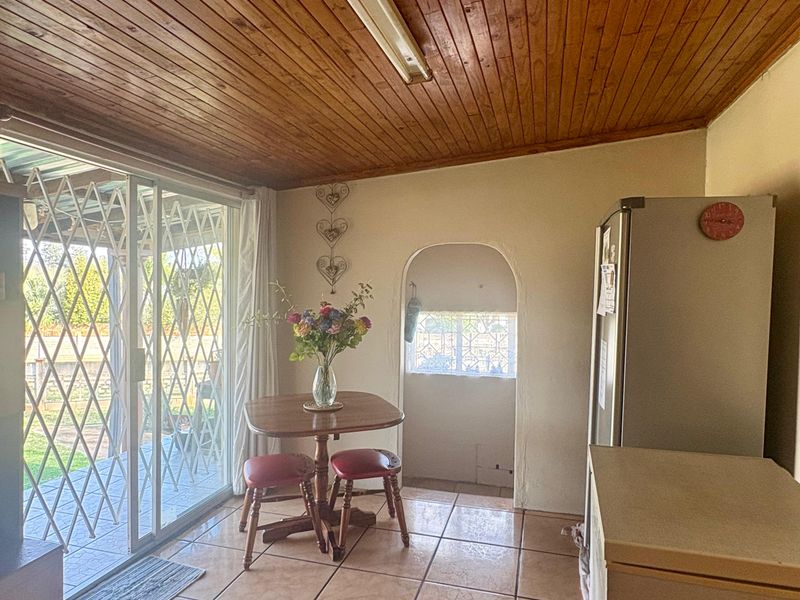 Open plan living area featuring timber tongue and groove ceiling, ceramic tiled flooring, and a sliding glass door with security gate leading to the exterior.