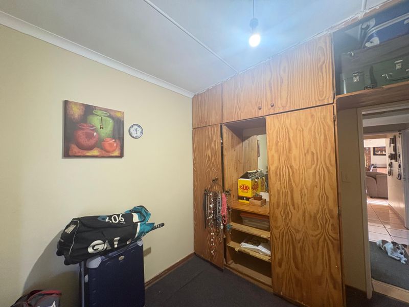 A bedroom featuring a large built-in wooden wardrobe with integrated shelving and storage, finished with standard cove cornicing.
