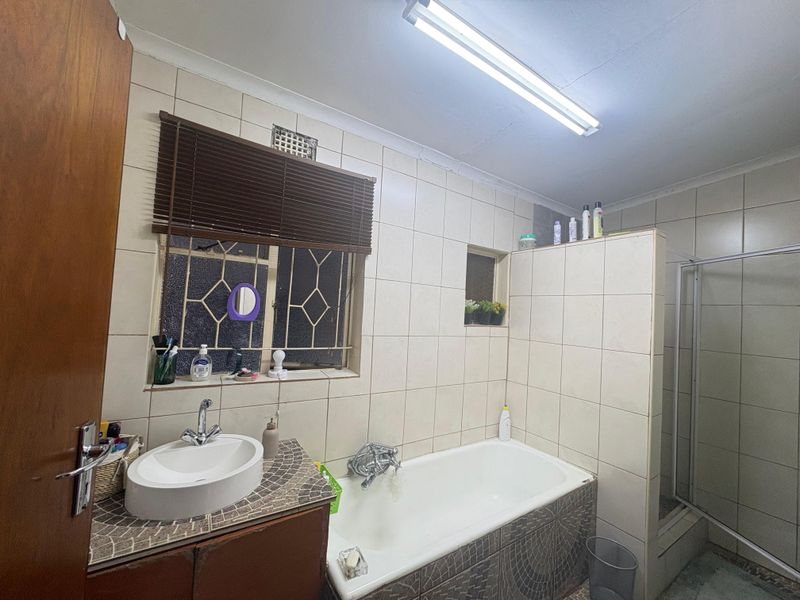 A functional bathroom featuring a built-in vanity with vessel sink, a bathtub, and a separate shower enclosure with tiled wall finishes.