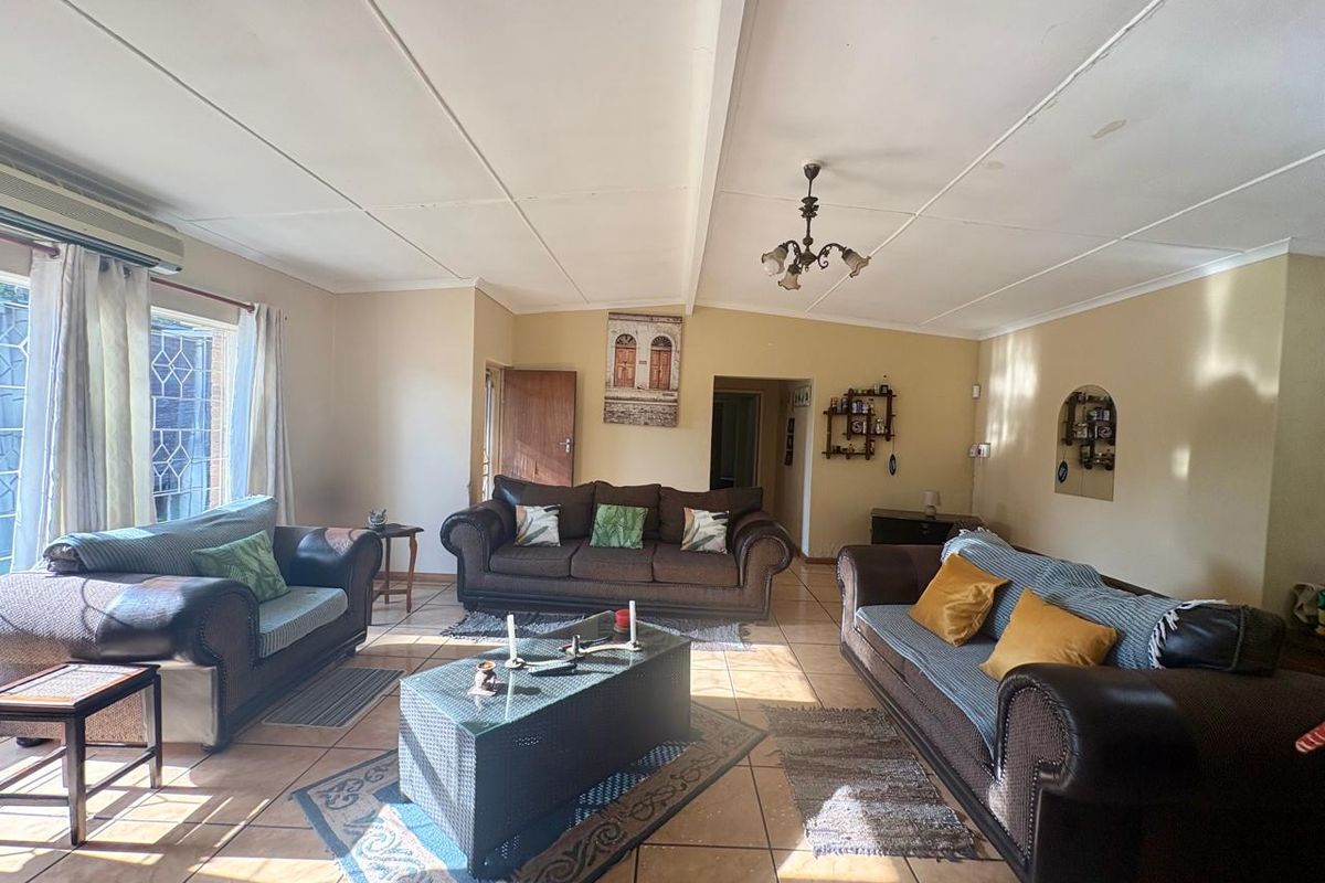 Spacious living room featuring tiled flooring, a wall-mounted air conditioning unit, and a decorative arched wall niche.