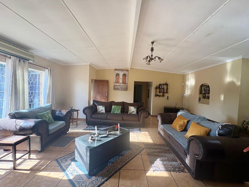 Spacious living room featuring tiled flooring, a wall-mounted air conditioning unit, and a decorative arched wall niche.