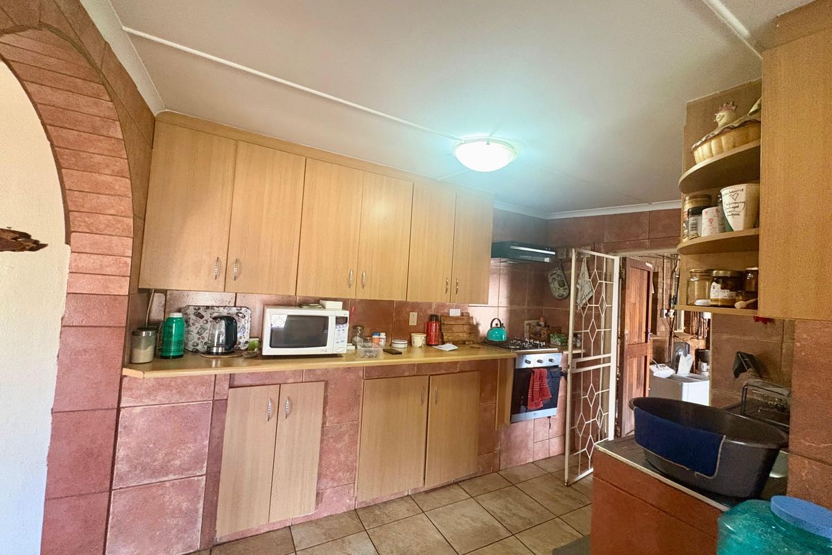 A dated kitchen featuring wood-look cabinetry, tiled splashbacks, and tiled flooring, with an integrated oven and extractor fan.
