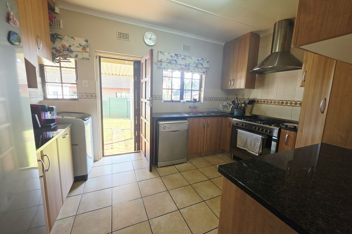 Functional kitchen featuring laminate cabinetry, granite countertops, a stainless steel extractor fan, gas stove, and direct access to the rear garden.