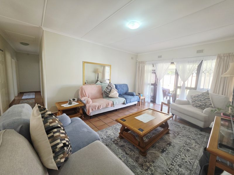 A spacious living room featuring terracotta floor tiles and large sliding glass doors that provide access to the outdoor area.