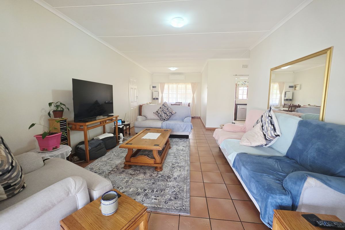 Spacious living room featuring tiled flooring, neutral wall finishes, and an integrated air conditioning unit, providing a comfortable and functional living space.