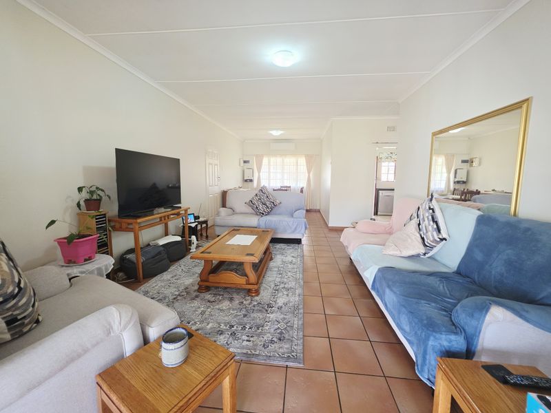 Spacious living room featuring tiled flooring, neutral wall finishes, and an integrated air conditioning unit, providing a comfortable and functional living space.