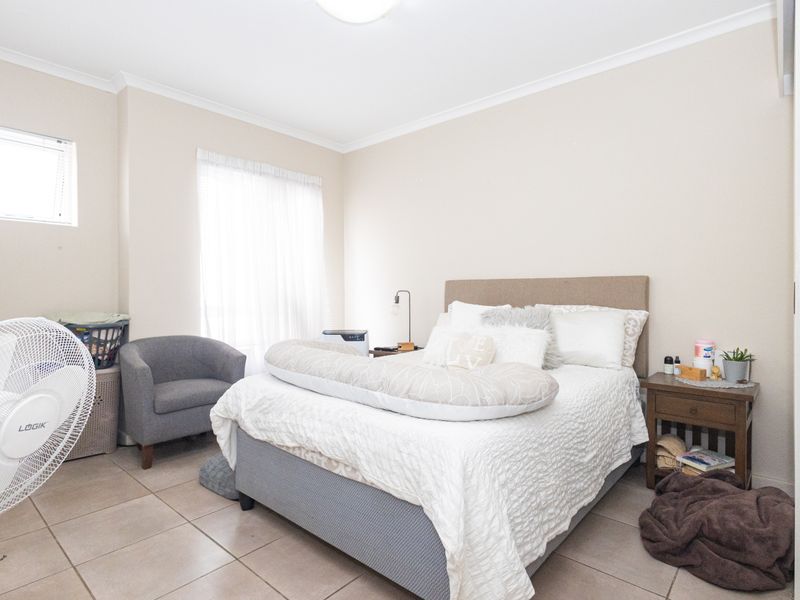 A well-lit bedroom featuring neutral wall tones, tiled flooring, and a built-in cupboard, providing a functional and comfortable living space.