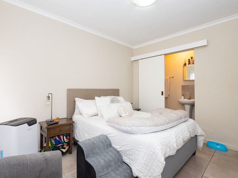 A bedroom featuring tiled flooring and a sliding door leading to an en-suite bathroom with a pedestal basin.