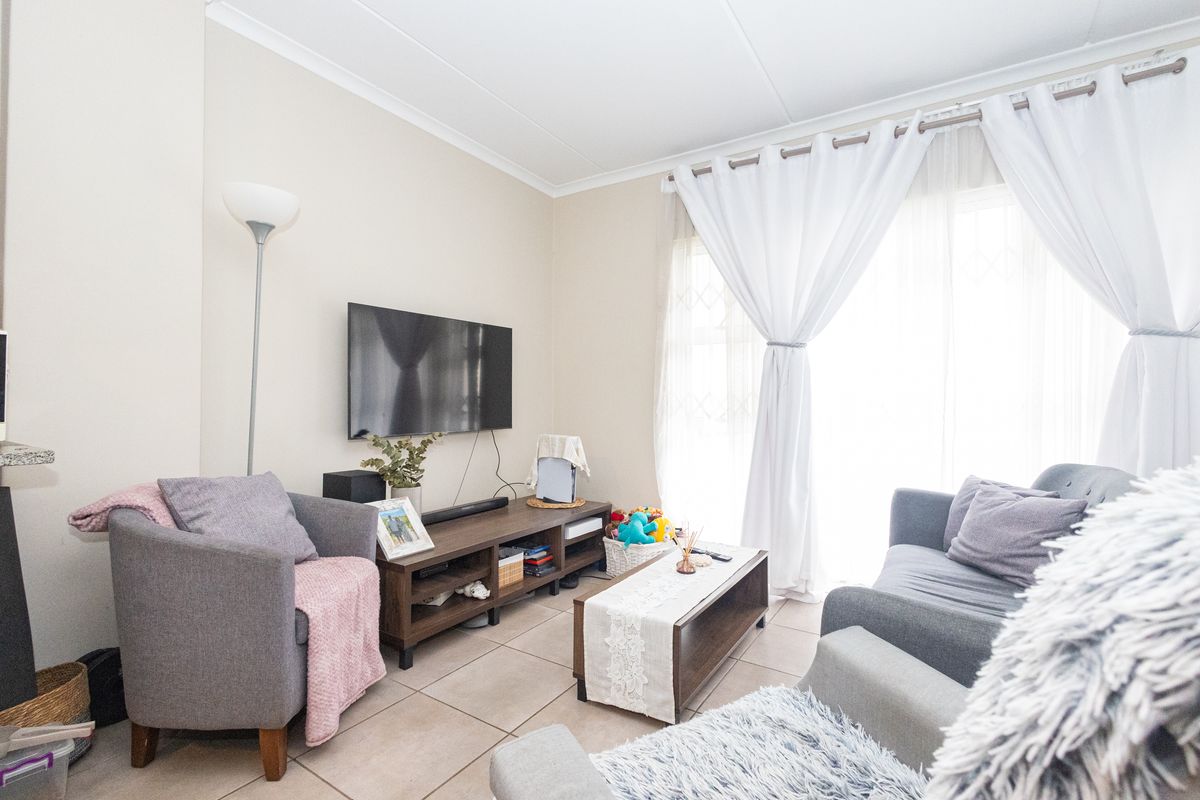 A comfortable living room featuring tiled flooring and a sliding glass door that provides natural light, creating a bright and inviting space.