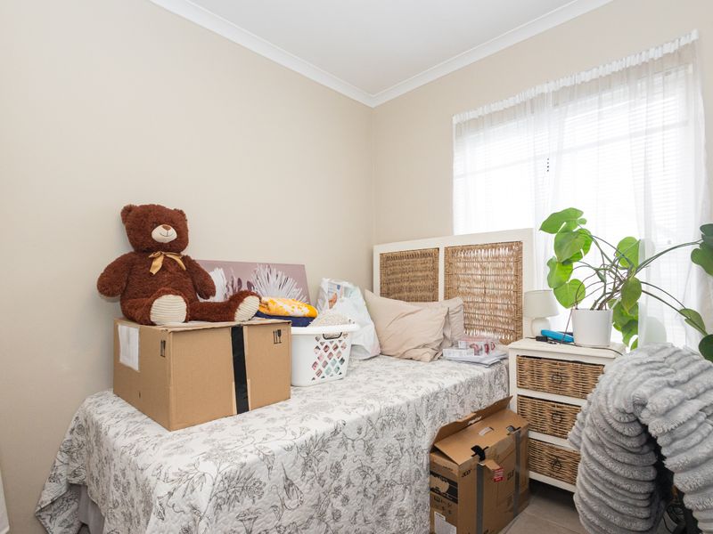 A bedroom featuring neutral wall tones, cove cornicing, and window treatments including blinds and sheer curtains.