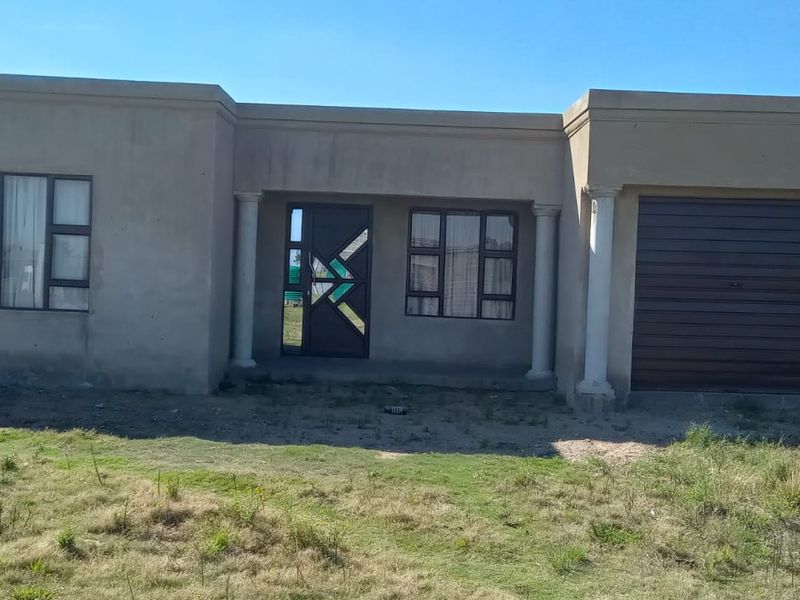 Front elevation of a single-story house featuring a garage, covered entrance with columns, and unfinished exterior wall surfaces.